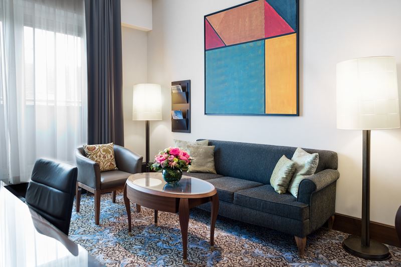 The Ritz-Carlton Vienna - димзайн интерьера номера с синим диваном и абстрактной картиной 