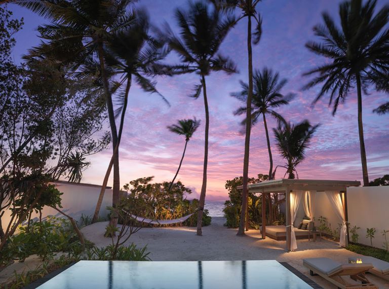 Курортный отель Fairmont Maldives Sirru Fen Fushi на Мальдивах - тропический закат с пальмами у бассейна 