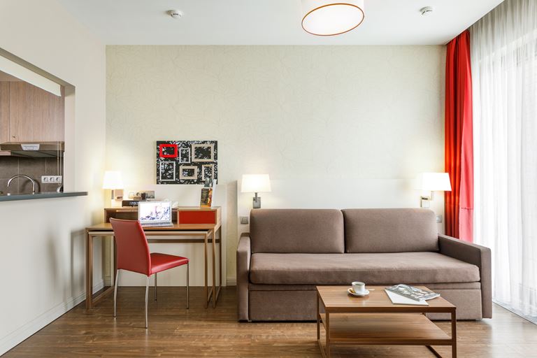 Апарт-отели Adagio – интерьер с бежевым диваном 